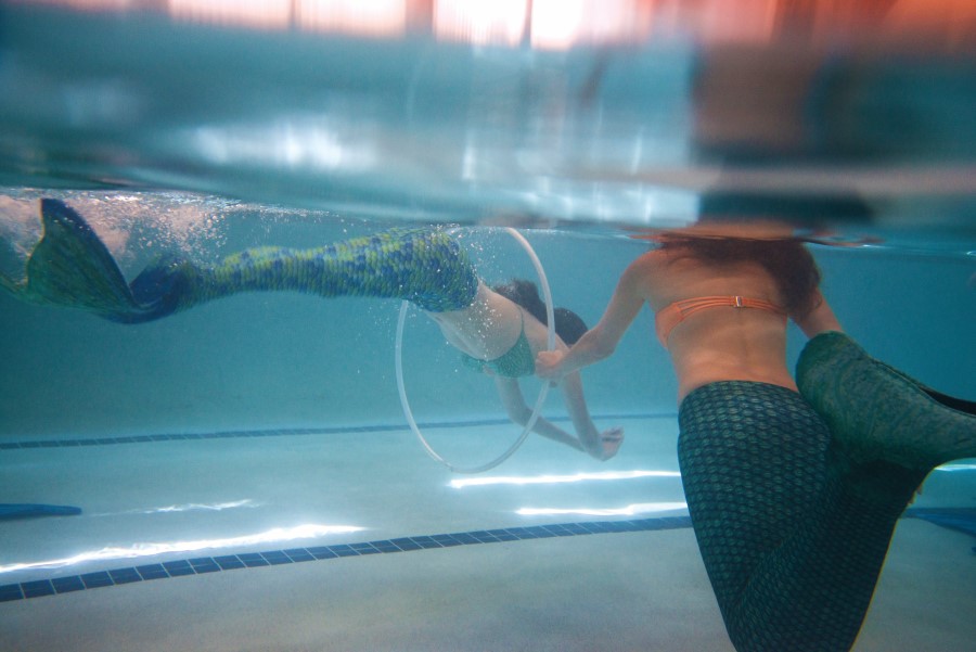 A mermaid swims through a hula hoop for practice